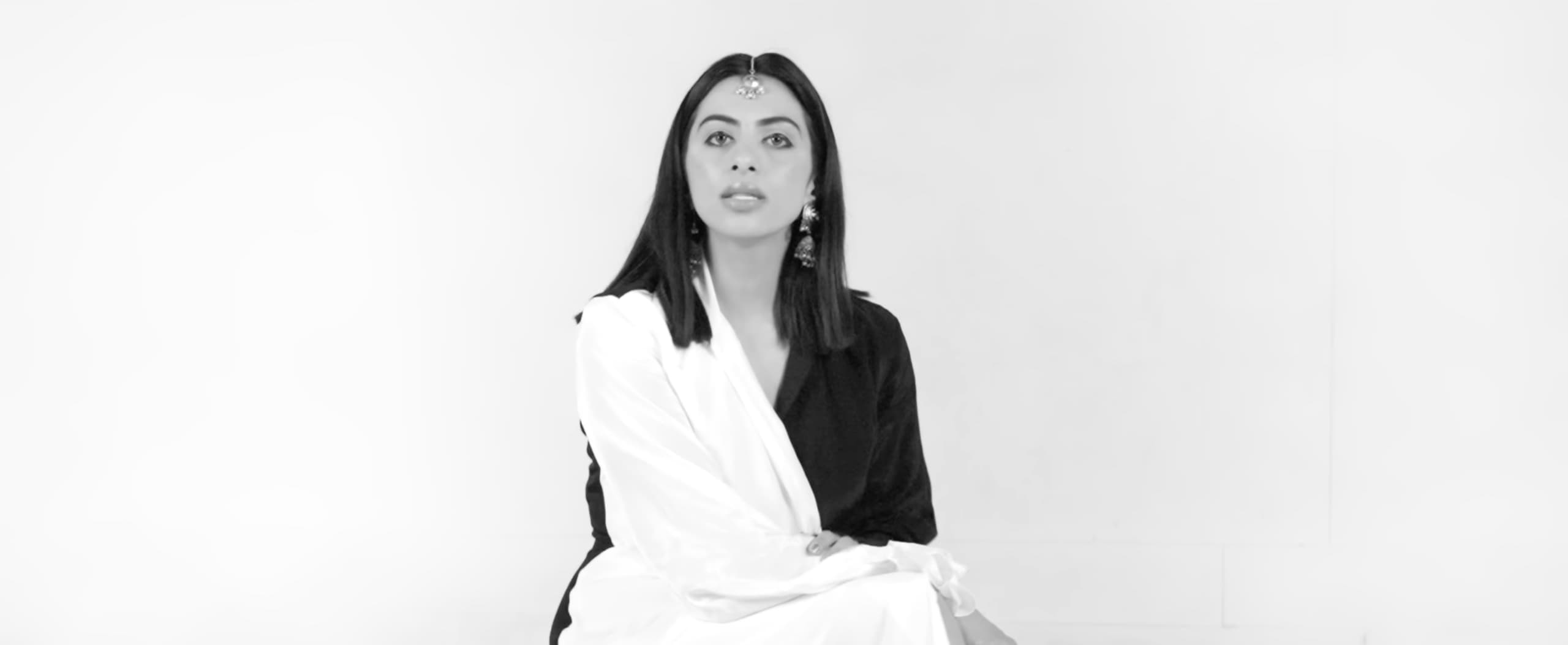 Studio portrait of Ranjani Murthy seated in black-and-white silk